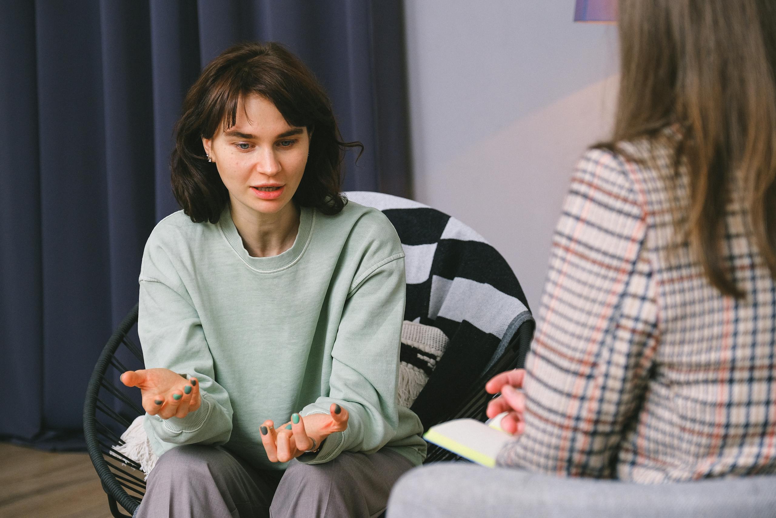 Calm female sitting on armchair and giving interview to concentrated woman in light room